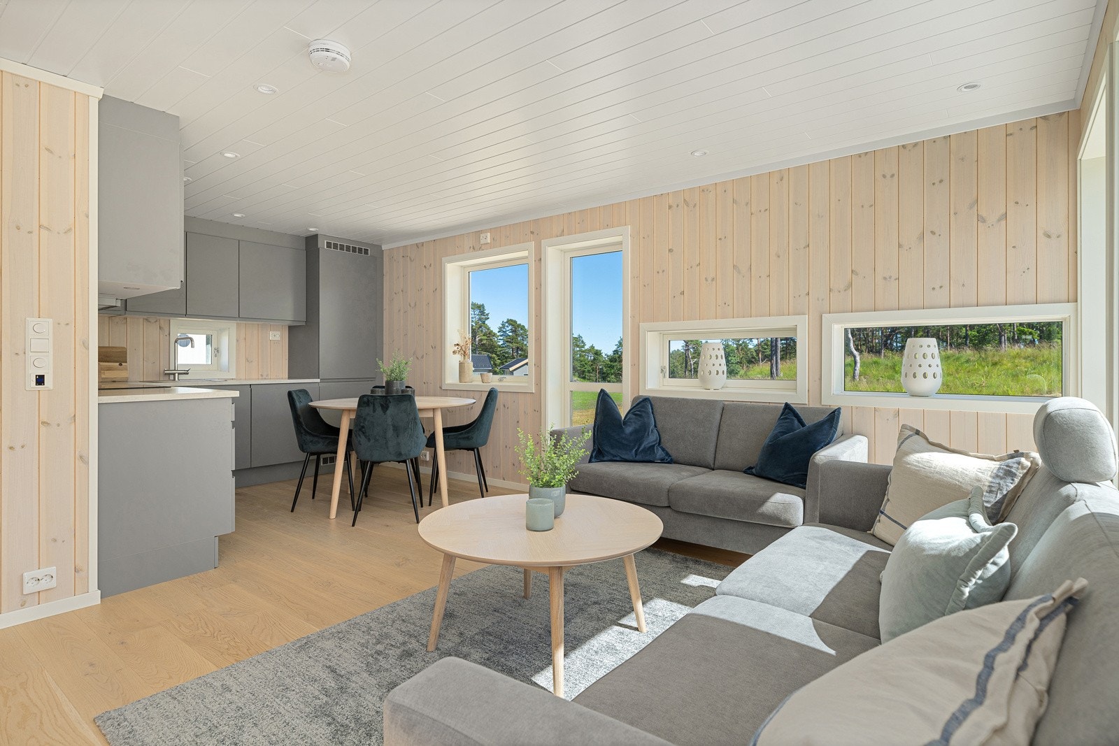 Det er terrassedør ut på to sider av stuen hvor det er betongdekke og stor hage Galleribilde