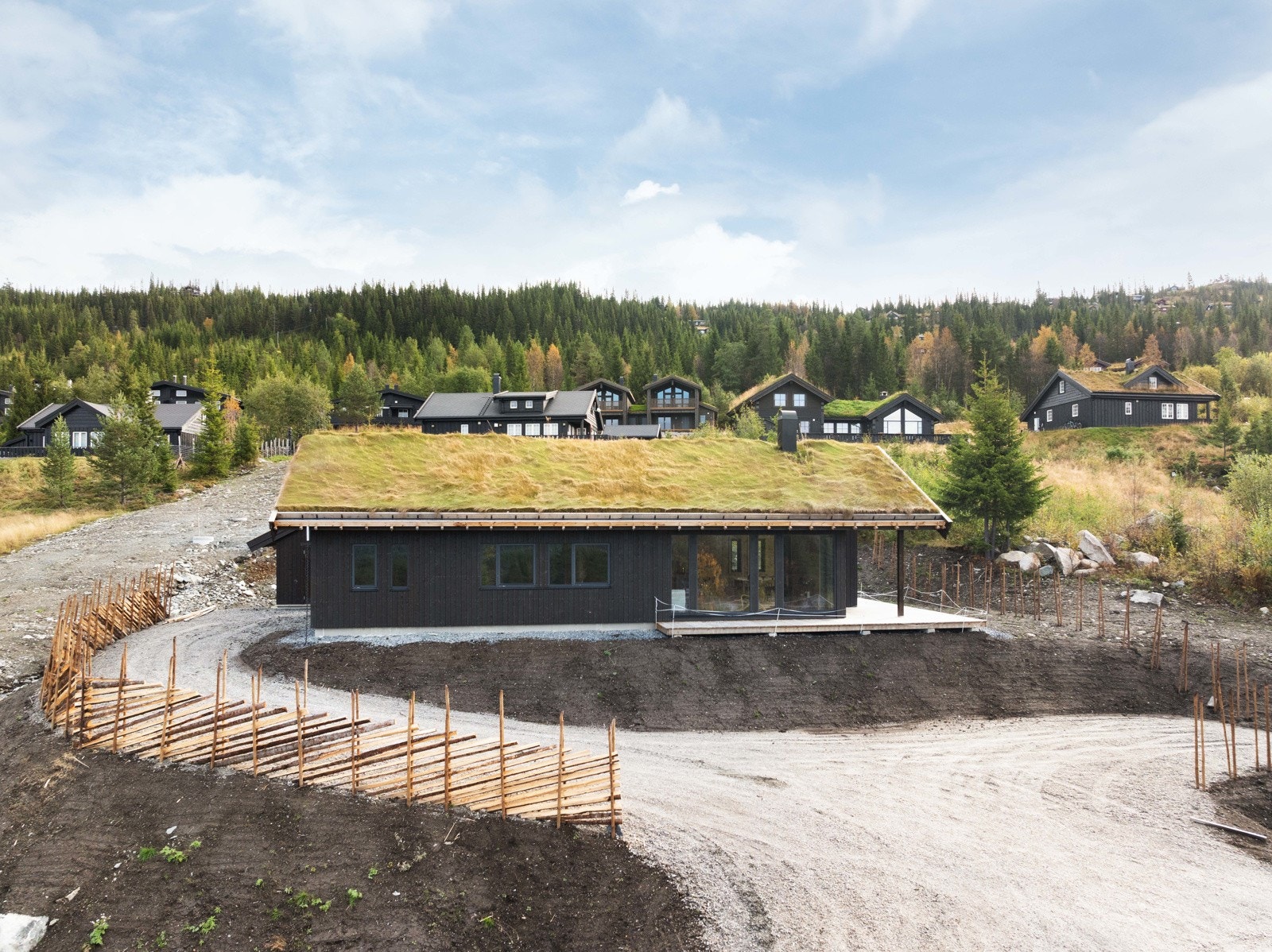 Hytta har flott grønt torvtak og oppsatt skigard rundt tomten Galleribilde