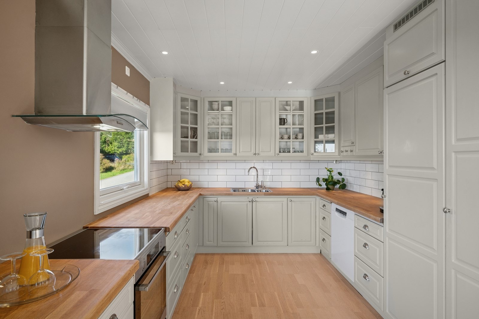 Innredning med malte profilerte fronter og heltre benkeplate med nedfelt kum i rustfritt stål. Galleribilde