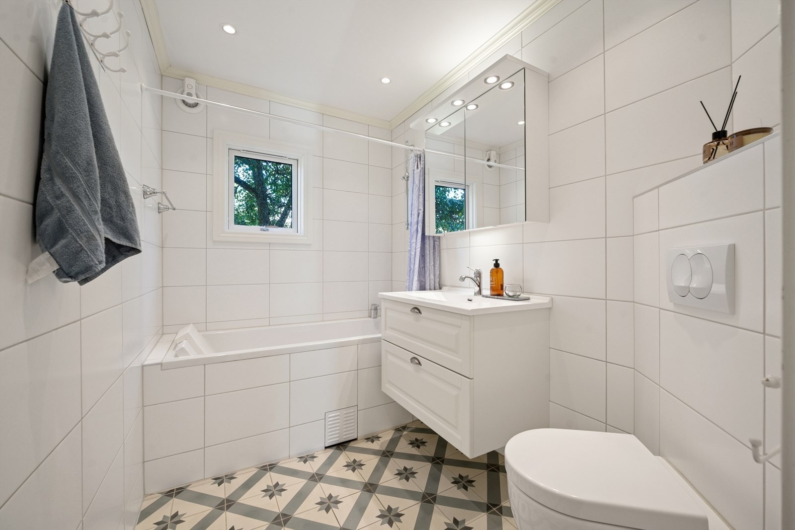 Fliselagt baderom med varmekabler i gulv, beliggende i første etasje. Badet er utstyrt med vegghengt toalett, innemurt badekar med dusj, baderomsinnredning og speilskap. Galleribilde