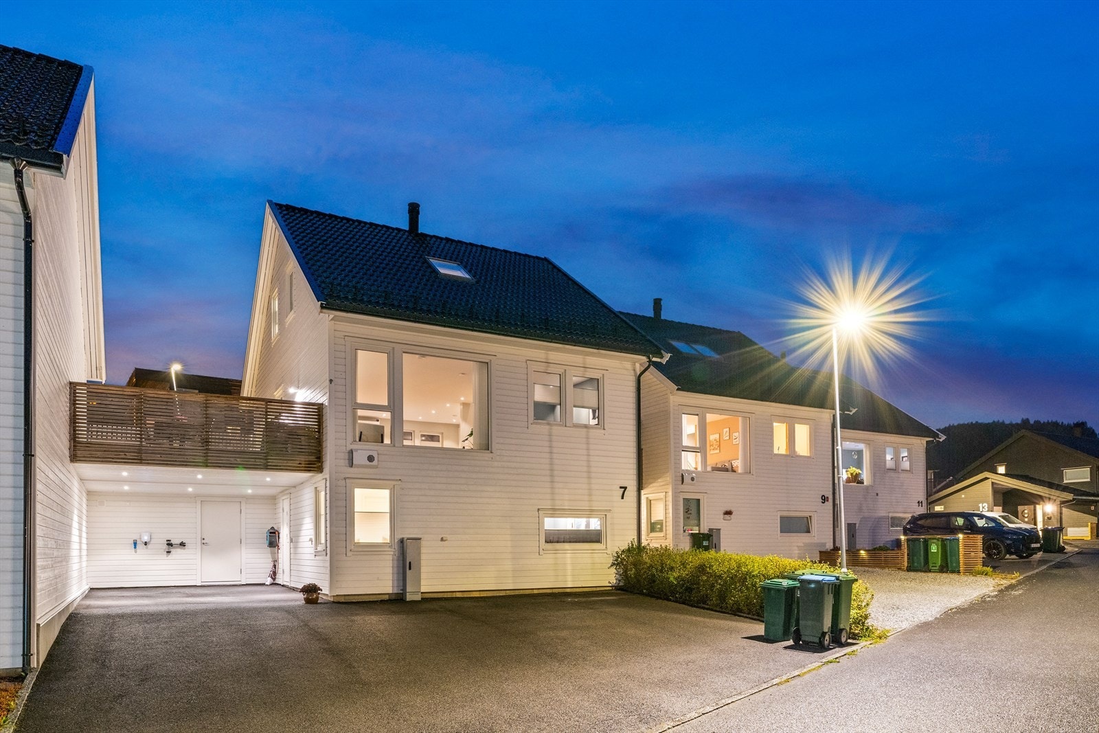 Eiendommen byr på bl.a. asfaltert gårdsplass, carport med elbillader og en inngjerdet hage. Galleribilde