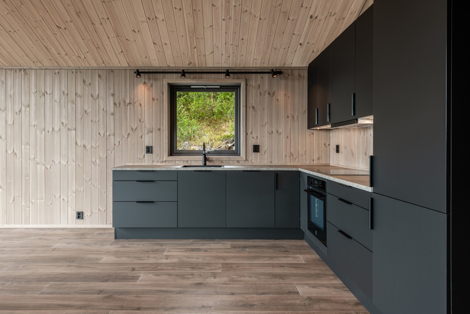 Fint kjøkken med mørke grå, glatte fronter. Galleribilde