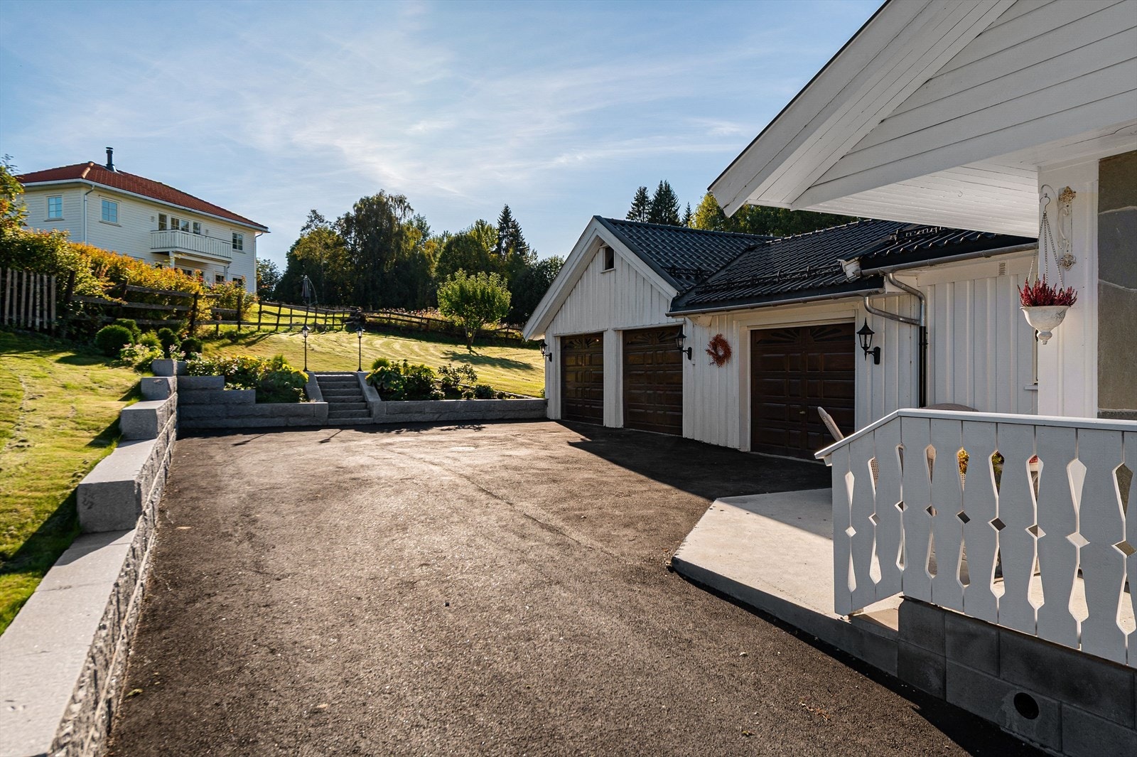 Asfaltert gårdsplass med gjennomført beplantning og imponerende granittmur som gir et stilfullt førsteinntrykk. Galleribilde