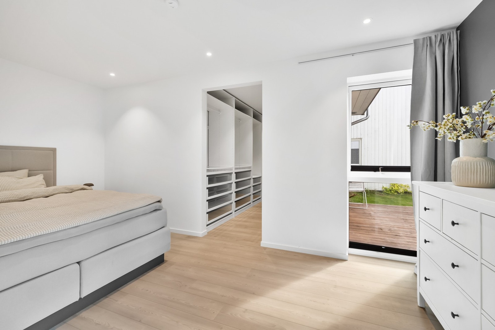 Lyst og behagelig hovedsoverom med romslig walk-in closet Galleribilde