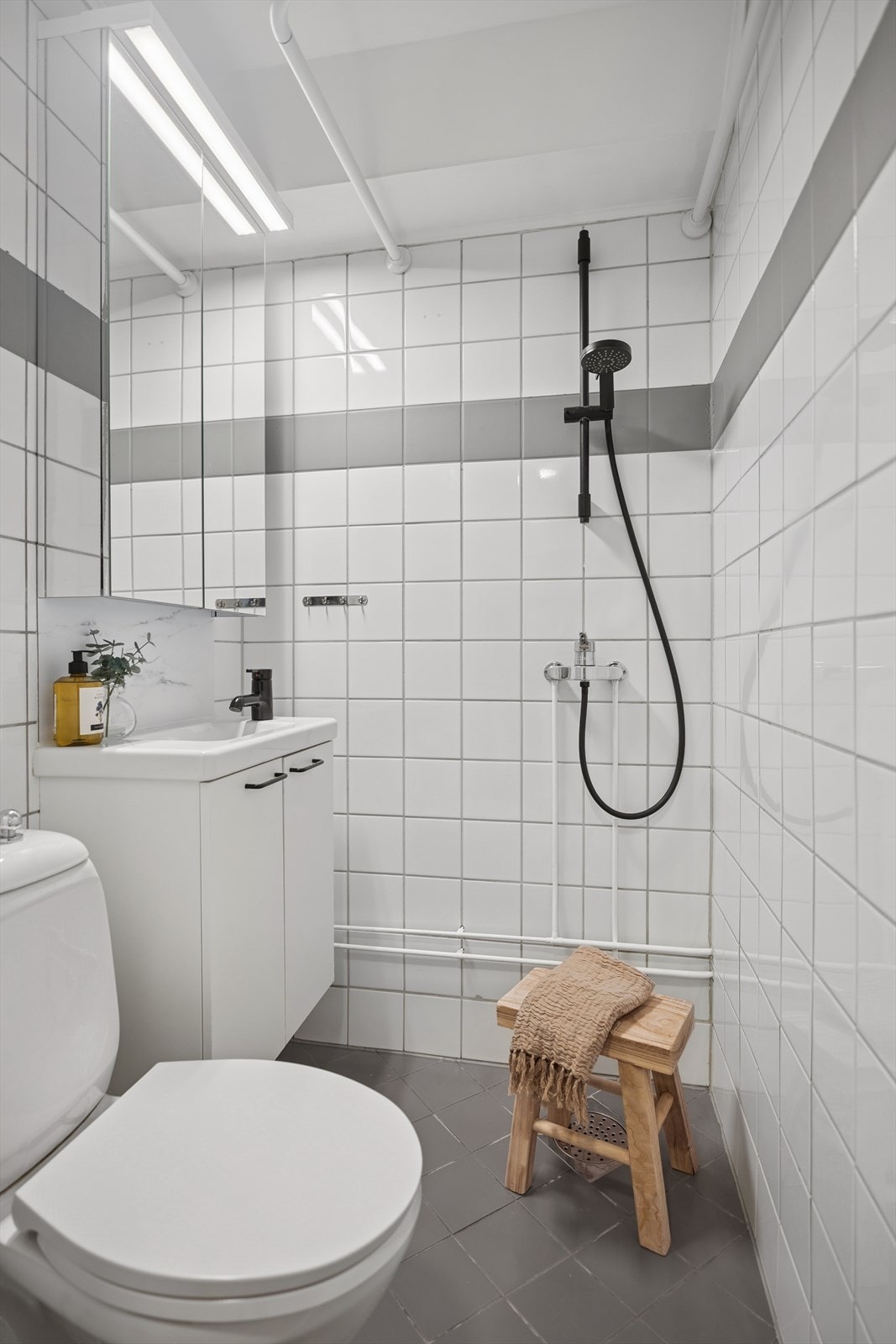 Bad/wc består av frittstående wc, servant m/underskap, overskap m/speilfronter og overlys, samt åpen dusj m/mulighet for forheng. Galleribilde