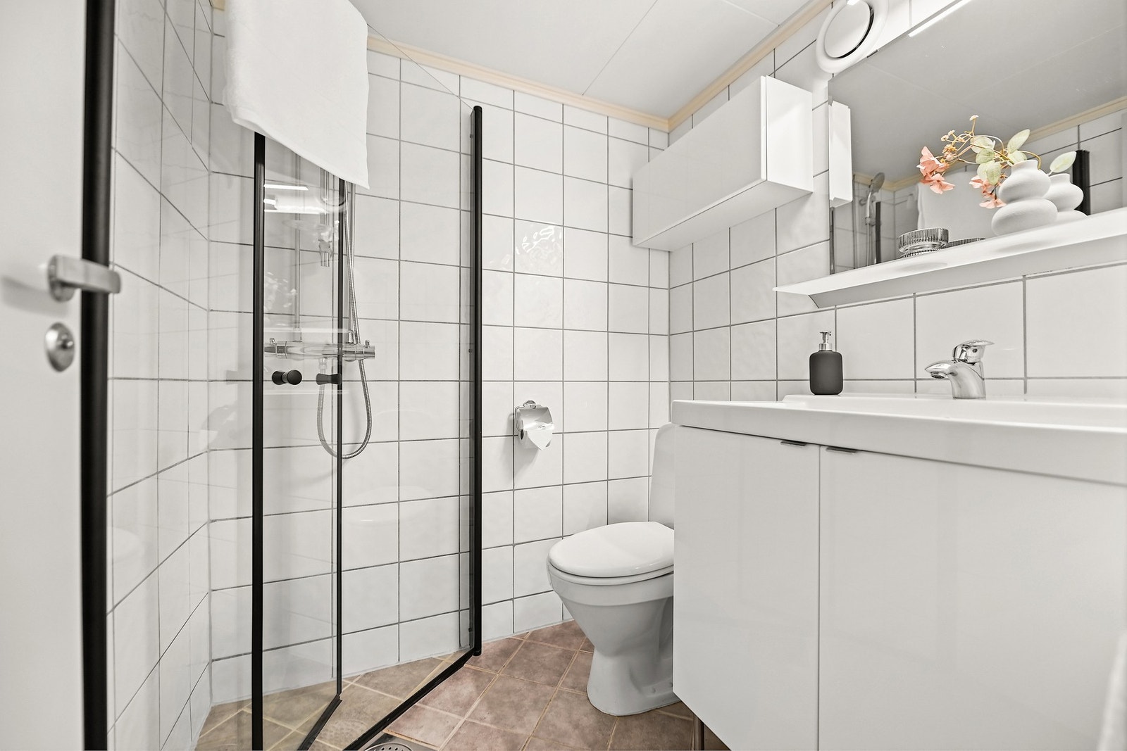 Badet er fra 2005 og det er varmekabler på gulvet. Det er montert nye dusjdører. Rommet har innredning med nedfelt servant, gulvfestet toalett og dusjhjørne. Galleribilde