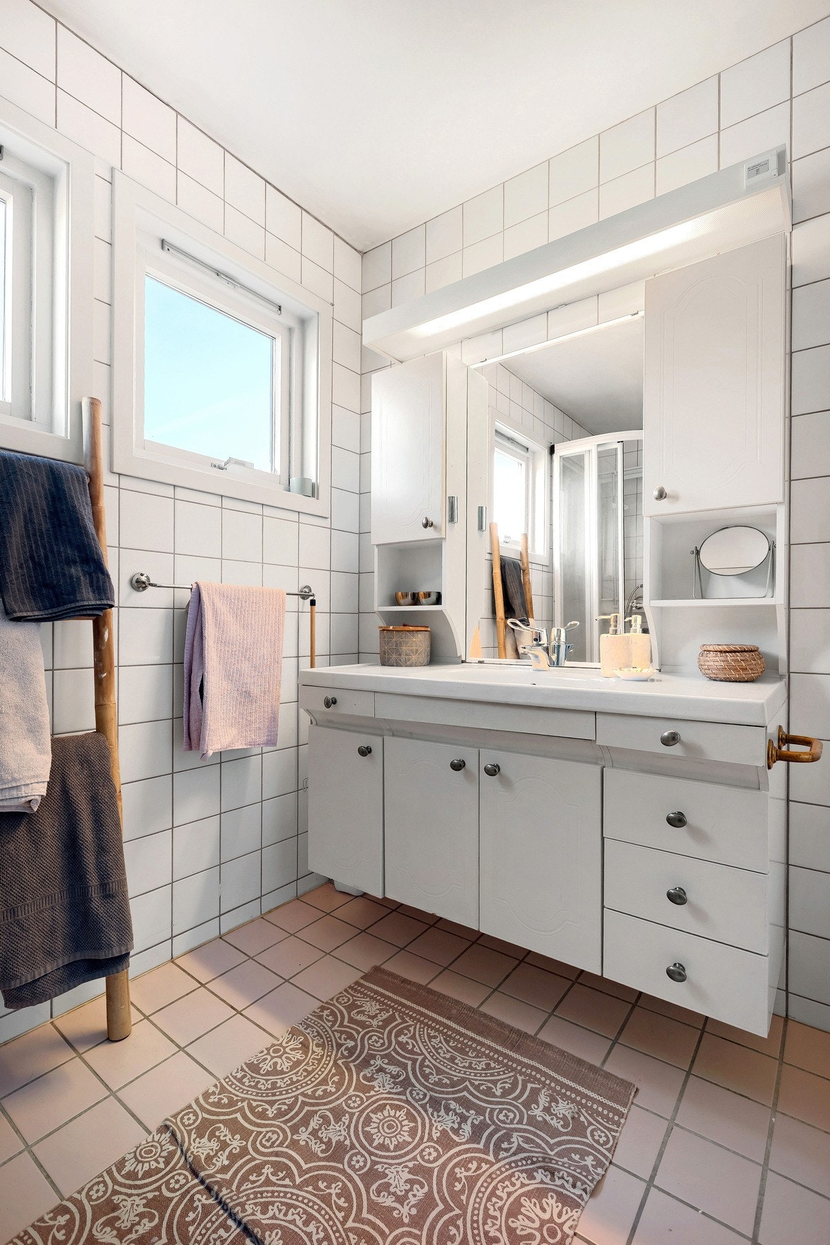 Baderomsinnredning med nedfelt servant, speil, overskap og belysning. Galleribilde