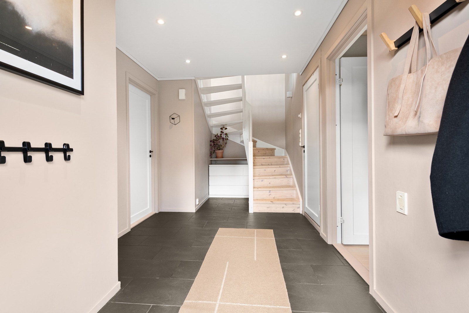 Gang/trapperom i 1. etasje med flislagt gulv, malte vegger og tak med innfelte spotter Galleribilde