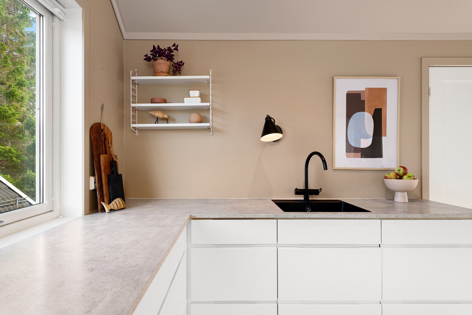 Det er integrert stekeovn, platetopp, oppvaskmaskin og kjøleskap. Vegghengt ventilator. Det er montert glassplate mellom kjøkkenbenk og overskap bak koketopp Galleribilde