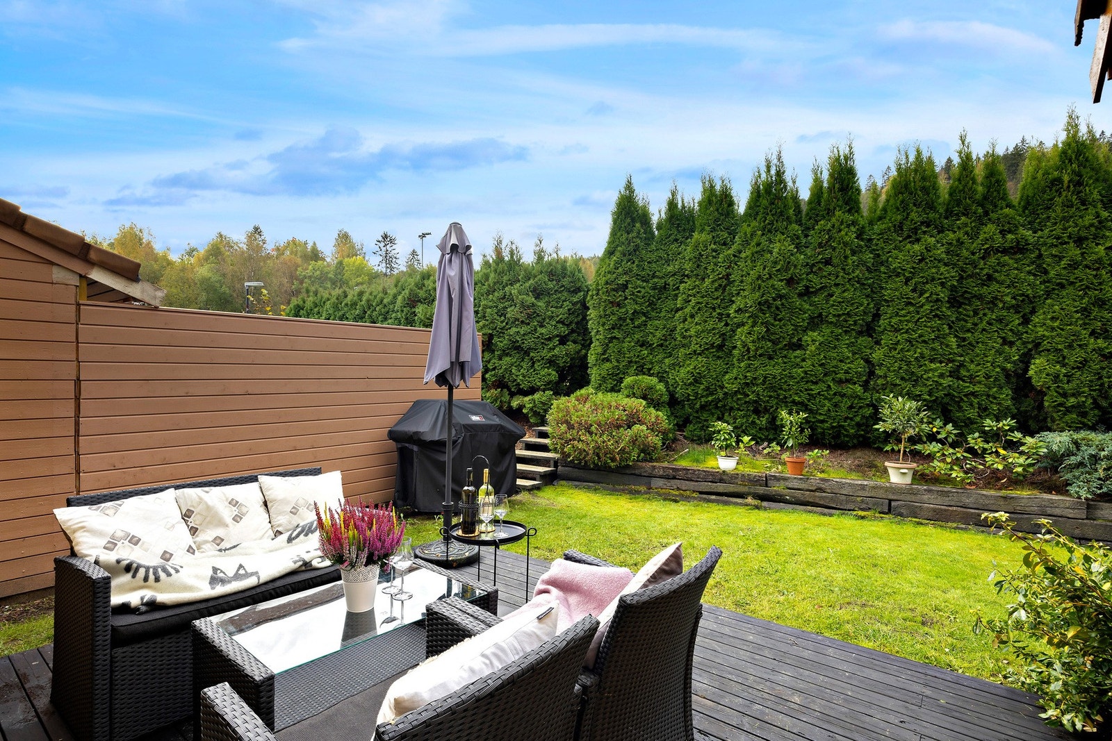 Hyggelig skjermet uteplass med platting og en velstelt hage. Galleribilde
