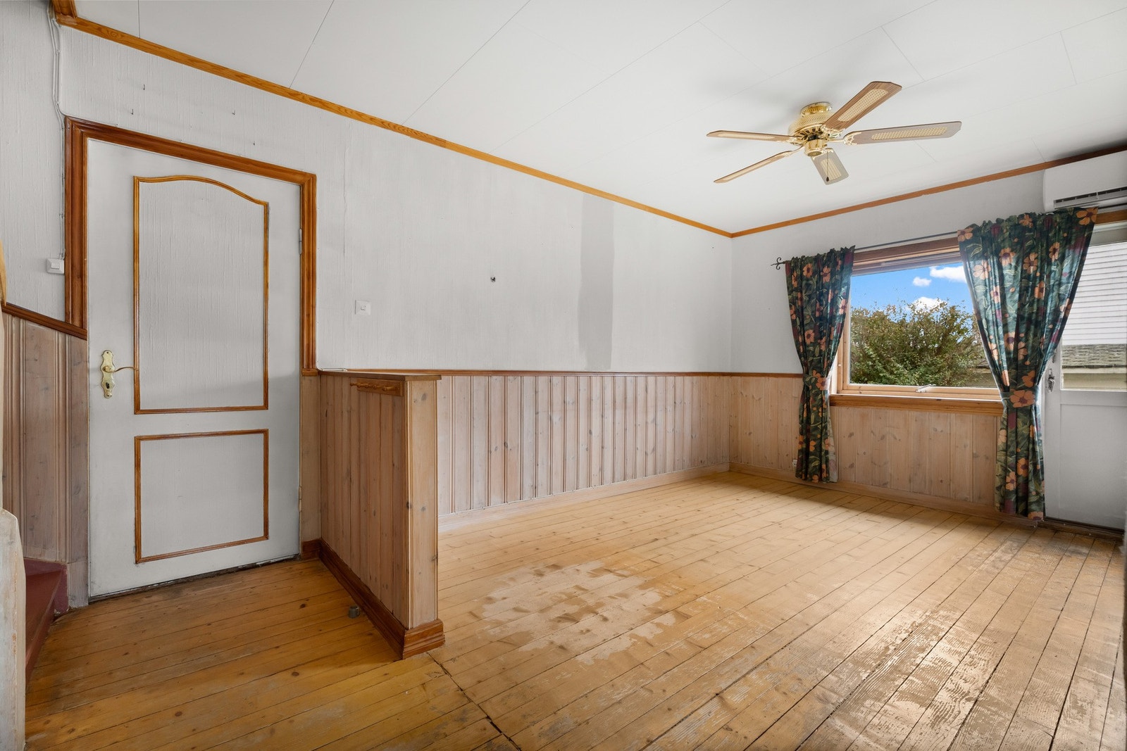 Stuen er romslig og lys med tapet/panel på vegger og furugulv Galleribilde