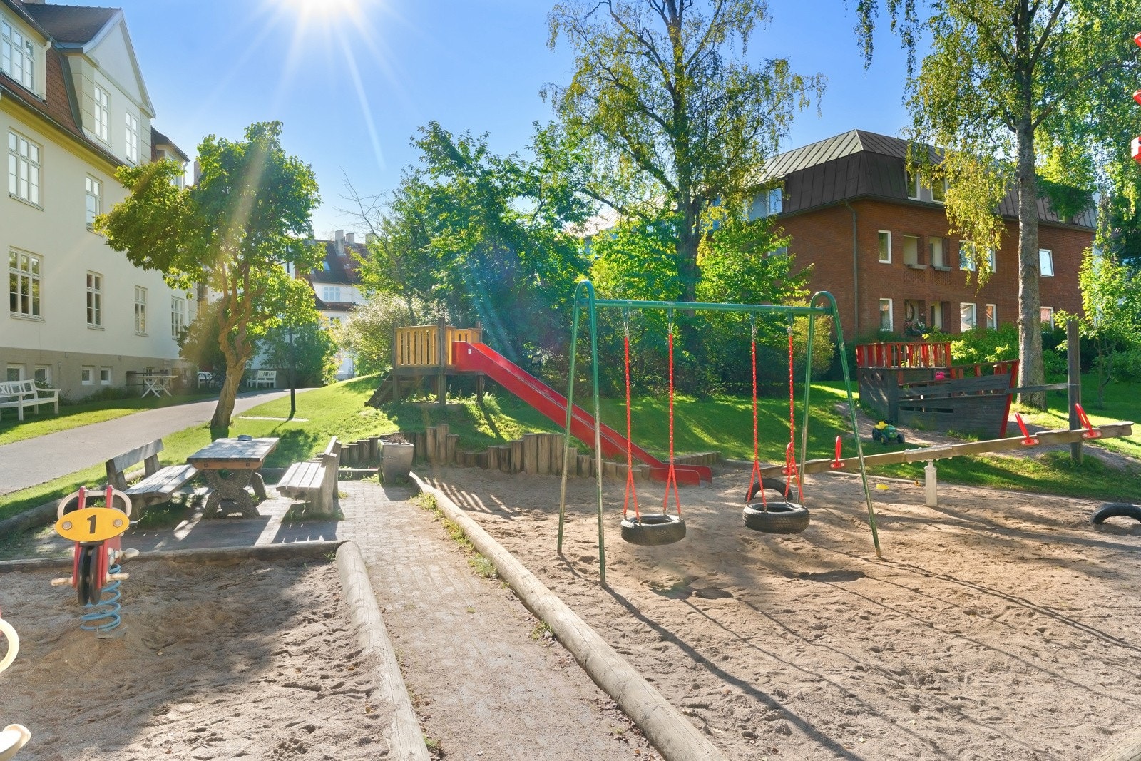 Idyllisk og rolig bakgård med flere sittegrupper, grill, lekeplass, og frodige forhager med møblering og beplantning Galleribilde