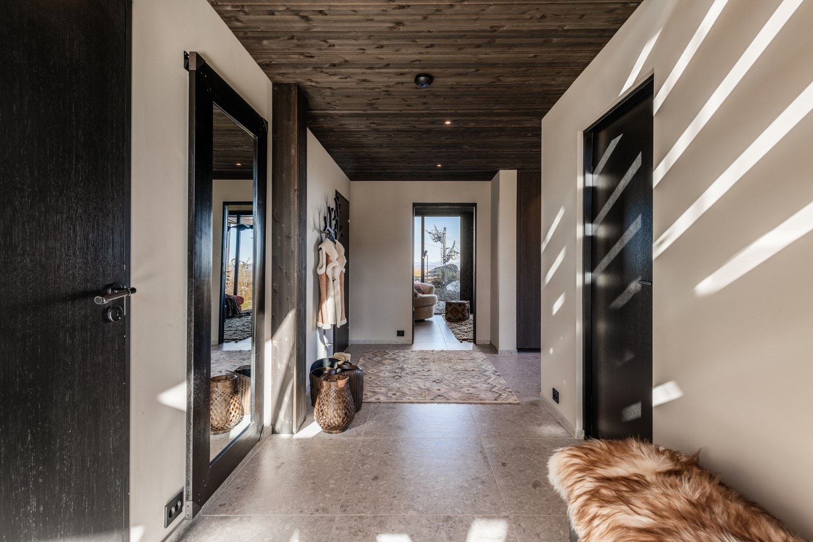 Langstrakt hall med flislagt gulv, i store fliser, og veggene har mørkt trepanel. Her er det god plass til oppbevaring av både sko og yttertøy. Galleribilde