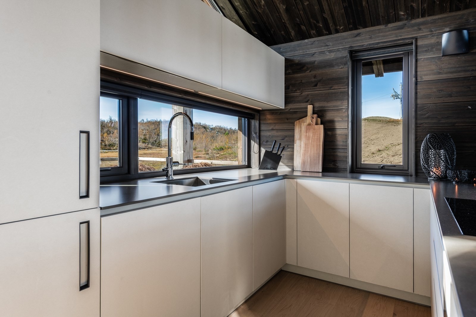 Lekkert kjøkken i glatt hvit utførelse og benkeplate av kvarts kompositt. Galleribilde