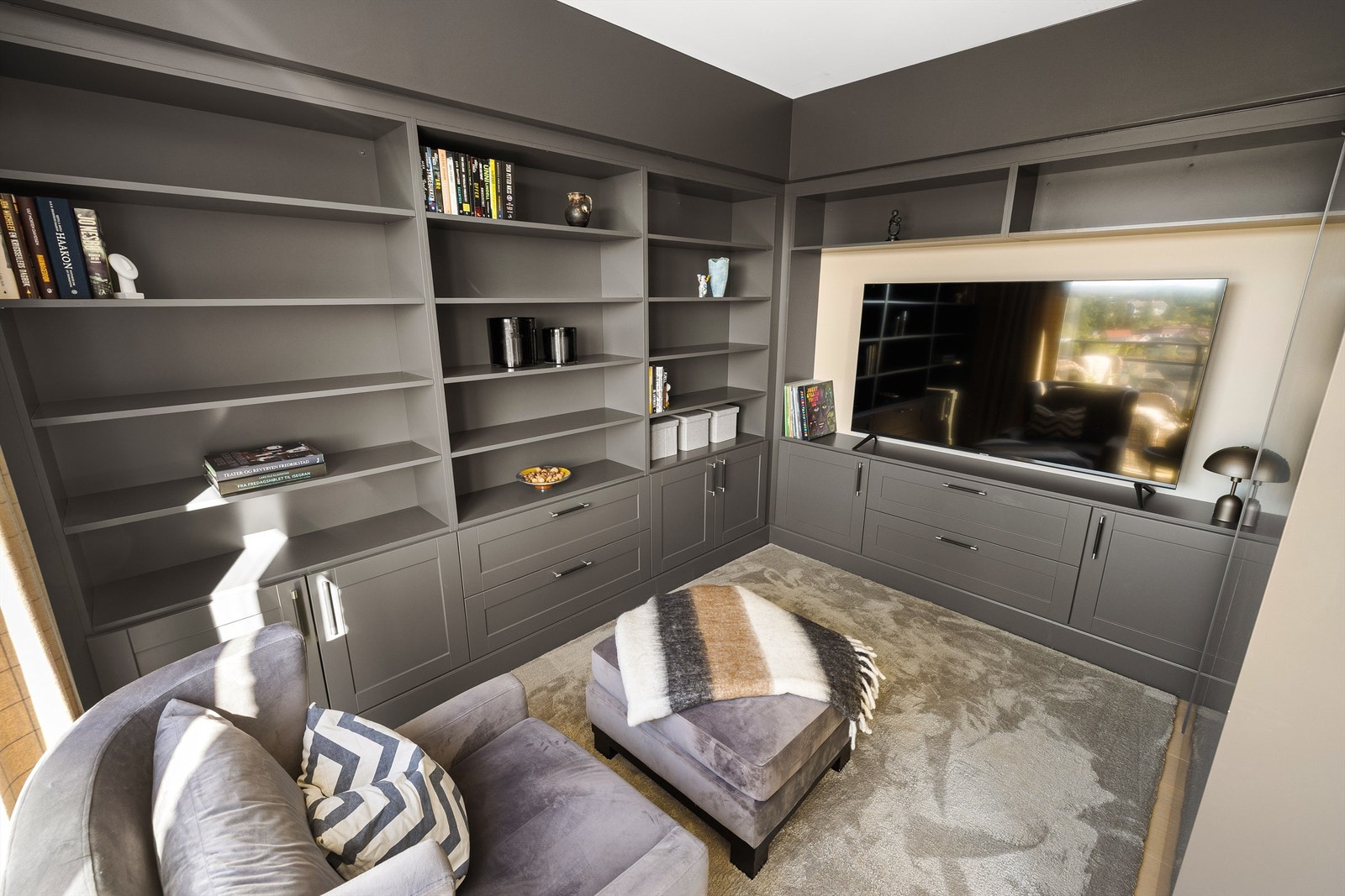 Ett soverom fyller i dag rollen som bibliotek/TV-stue, med skreddersydd plassbygget innredning. Galleribilde