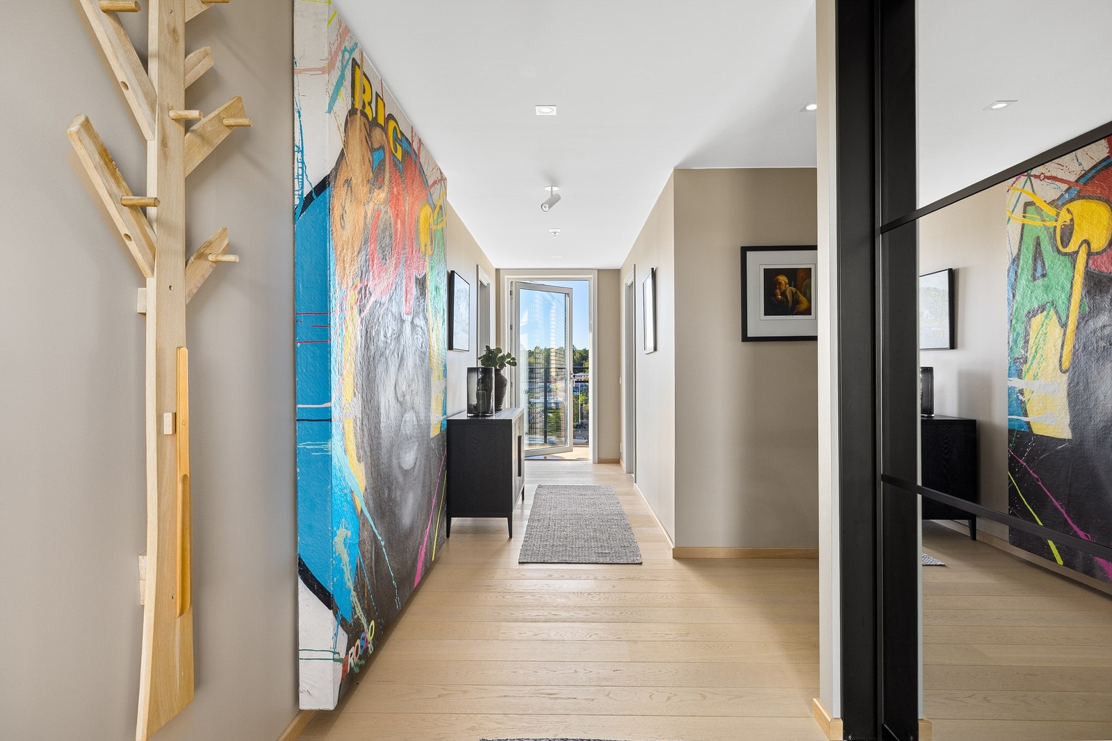 Balkongdører i glass gir siktlinje gjennom entreen og slipper dagslyset inn fra begge sider. Galleribilde