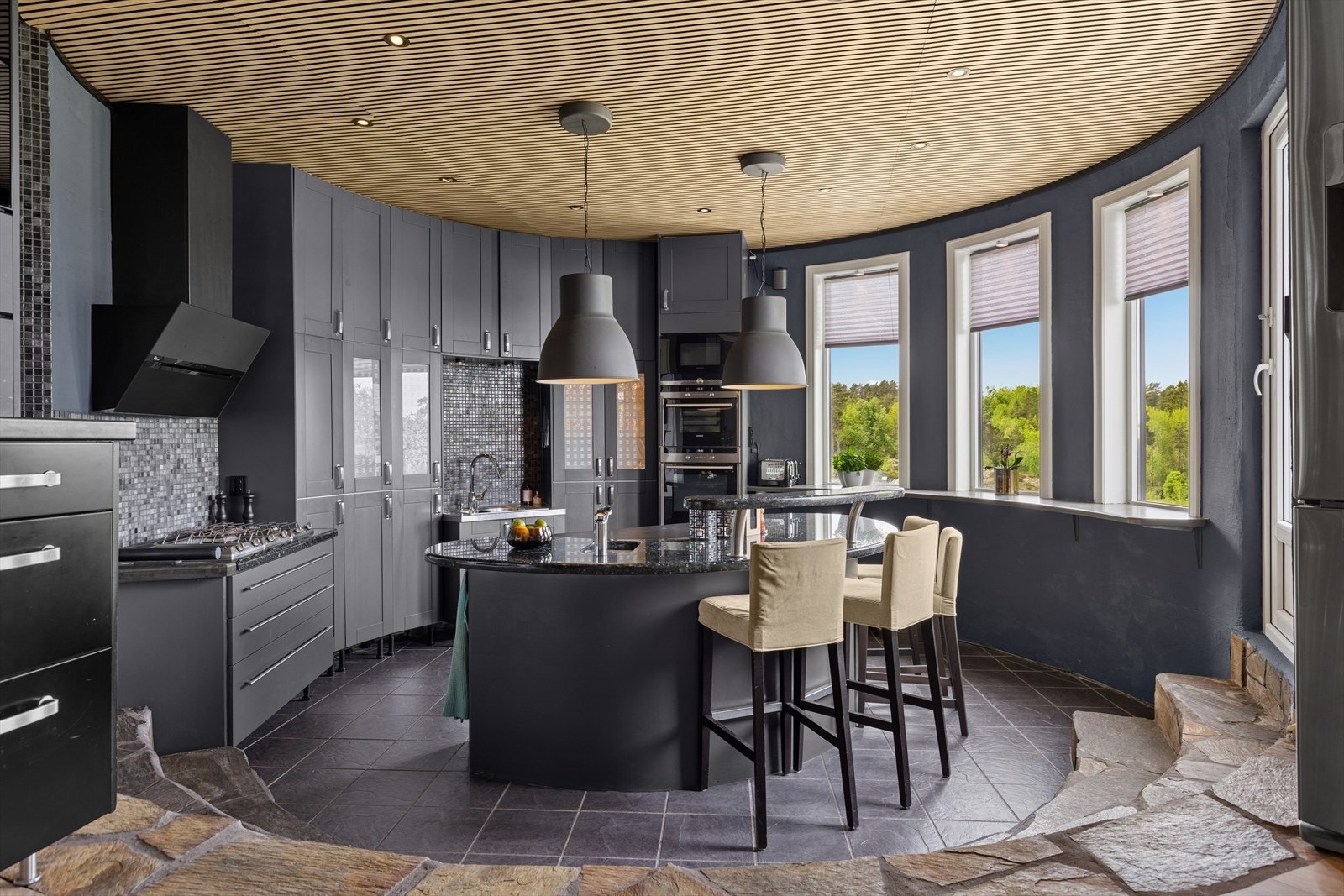 Et unikt, sirkulært kjøkken på 17 kvm med spesialtilpassede løsninger, flislagt gulv og benkeplate i eksklusiv Larviktit-stein. Galleribilde