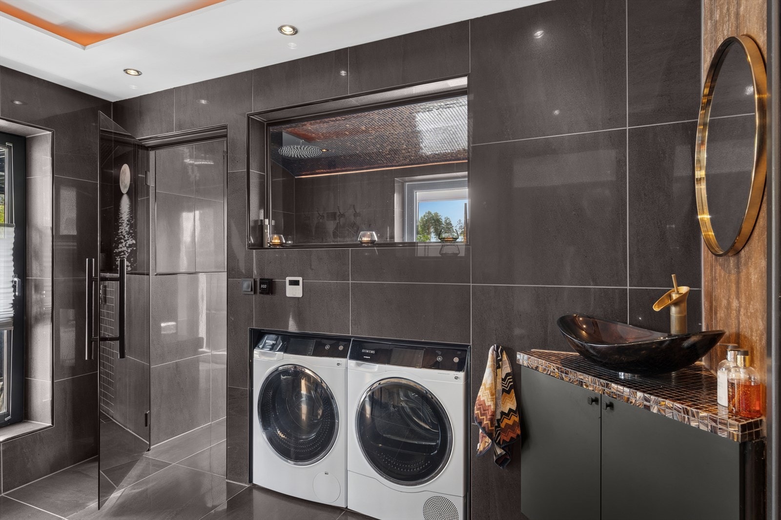 Et funksjonelt og elegant vaskerom med flislagte gulv og vegger. Galleribilde