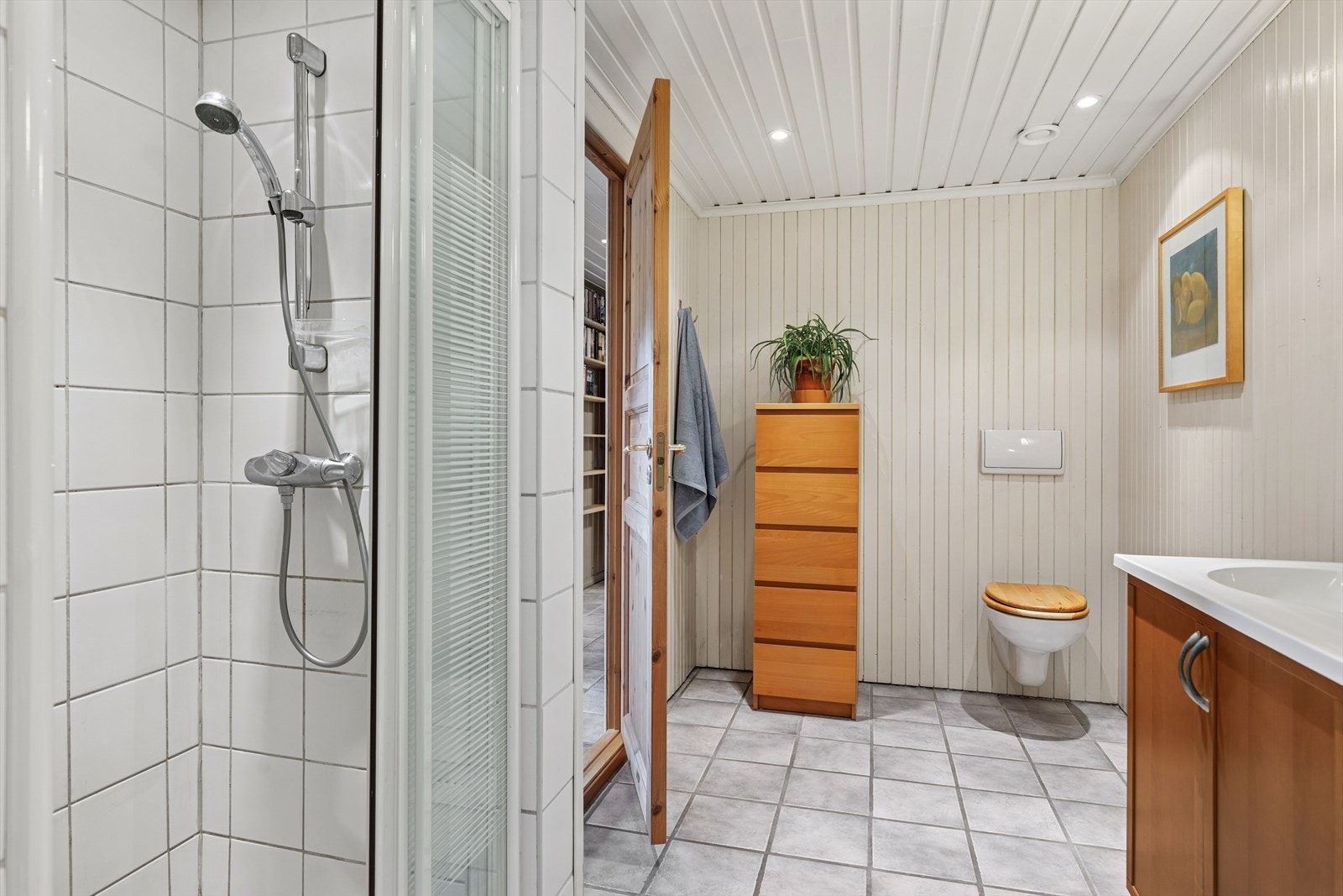 Bade er utstyrt med veggmontert toalett, servant, dusj samt god oppbevaringsplass Galleribilde