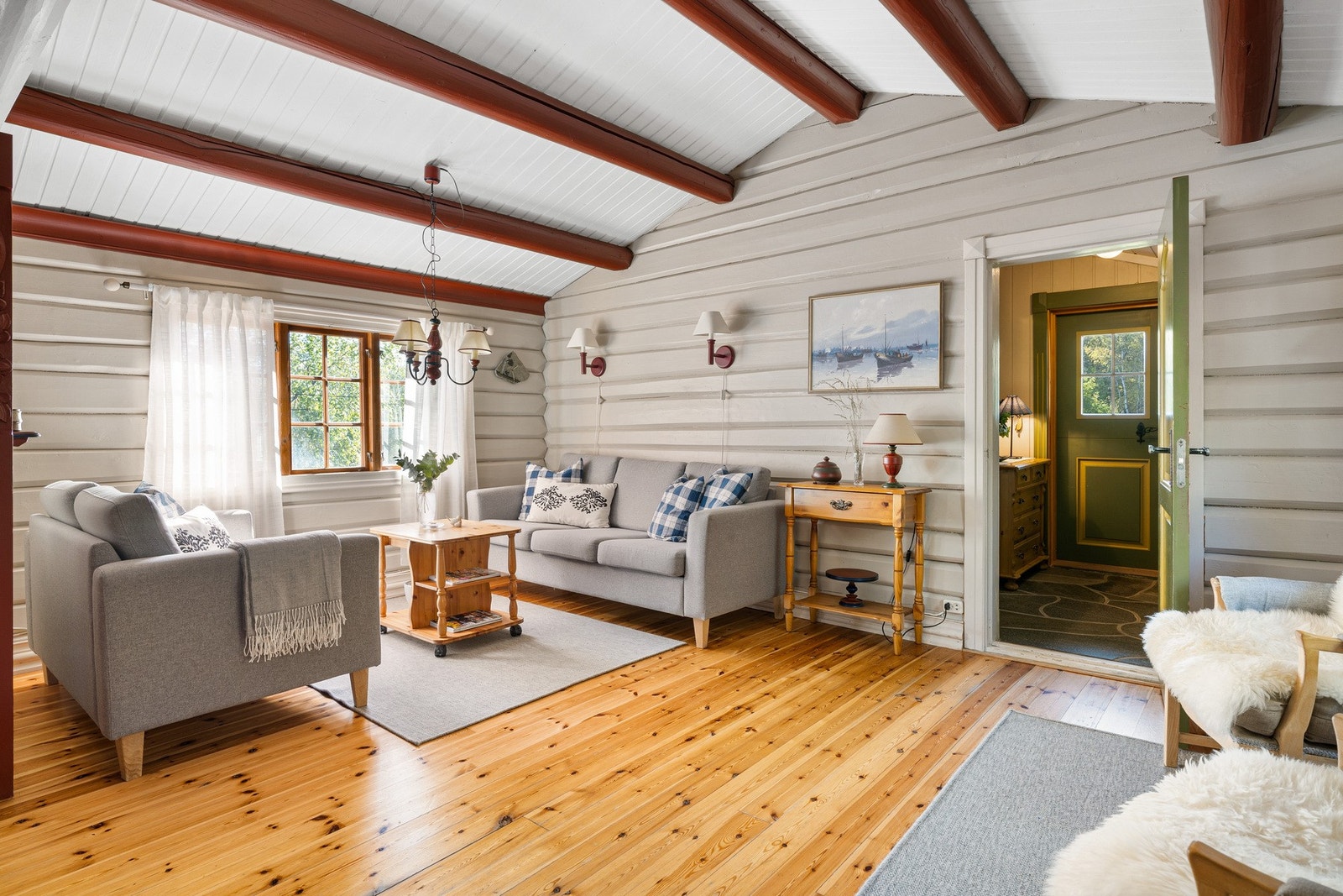 Sjarmerende stue med mørkerøde takbjelker og lyse tømmervegger som gir et klassisk preg. Galleribilde