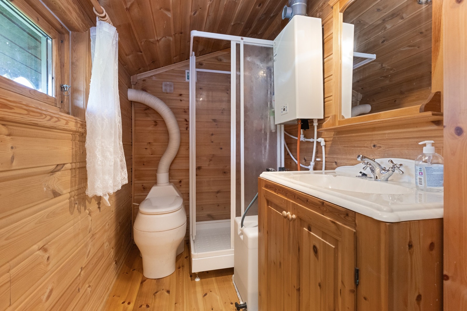 Hyttebad med dusjkabinett, komposttoalett og innredning med underskap og nedfelt servant Galleribilde