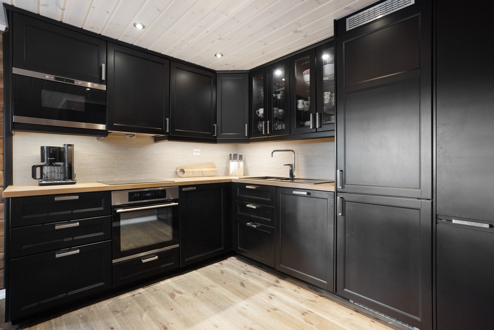 Flott kjøkken med moderne sorte, profilerte fronter. Benkeplaten er i heltre. Innredningen har forøvrig integerte hvitevarer og godt med oppbevaringsplass i skuffer og skap Galleribilde