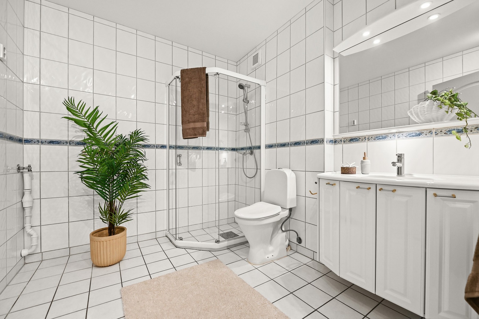 Badet er innredet med nedfelt servant, gulvfestet toalett, dusjhjørne og opplegg for vaskemaskin. Galleribilde