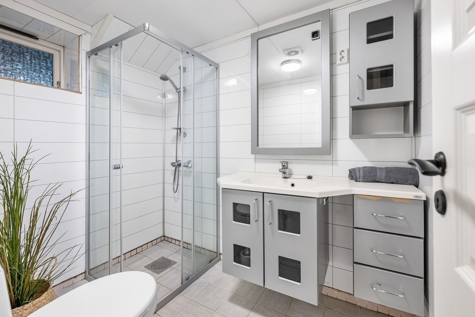 Helfliset bad innredet med baderomsinnredning med servant, toalett og dusj. Galleribilde