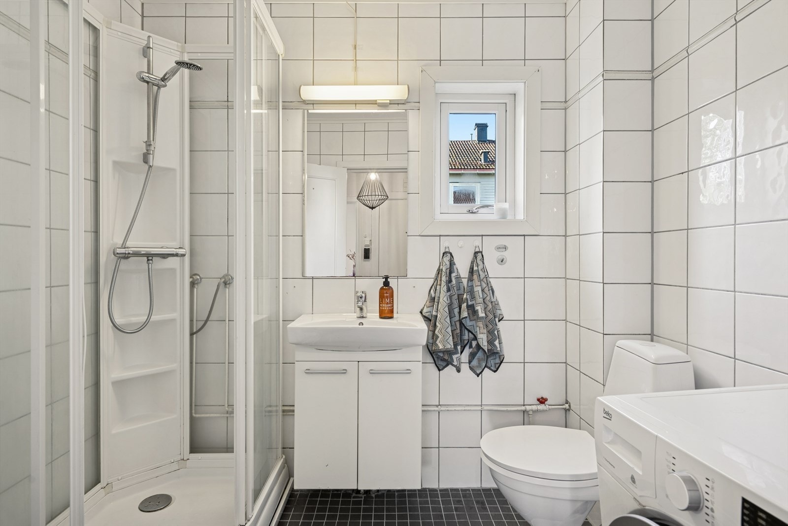 Et lyst og praktisk bad med flislagte overflater og varmekabler i gulv. Galleribilde