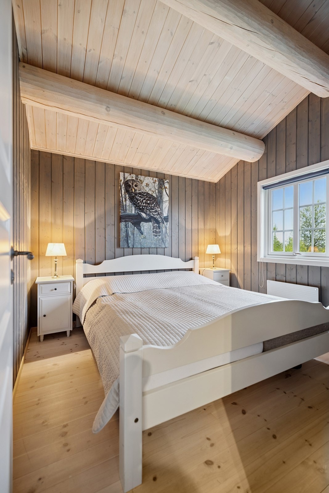 Rommet har panelte overflater og synlige, hvitbehandlede tømmeråser i himlingen. Galleribilde