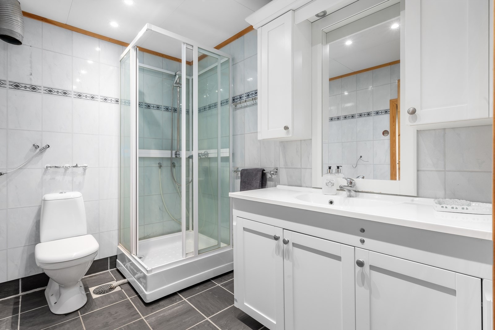 Badet er utstyrt med dusjkabinett, naturlig avtrekk, servantskap og wc. Galleribilde