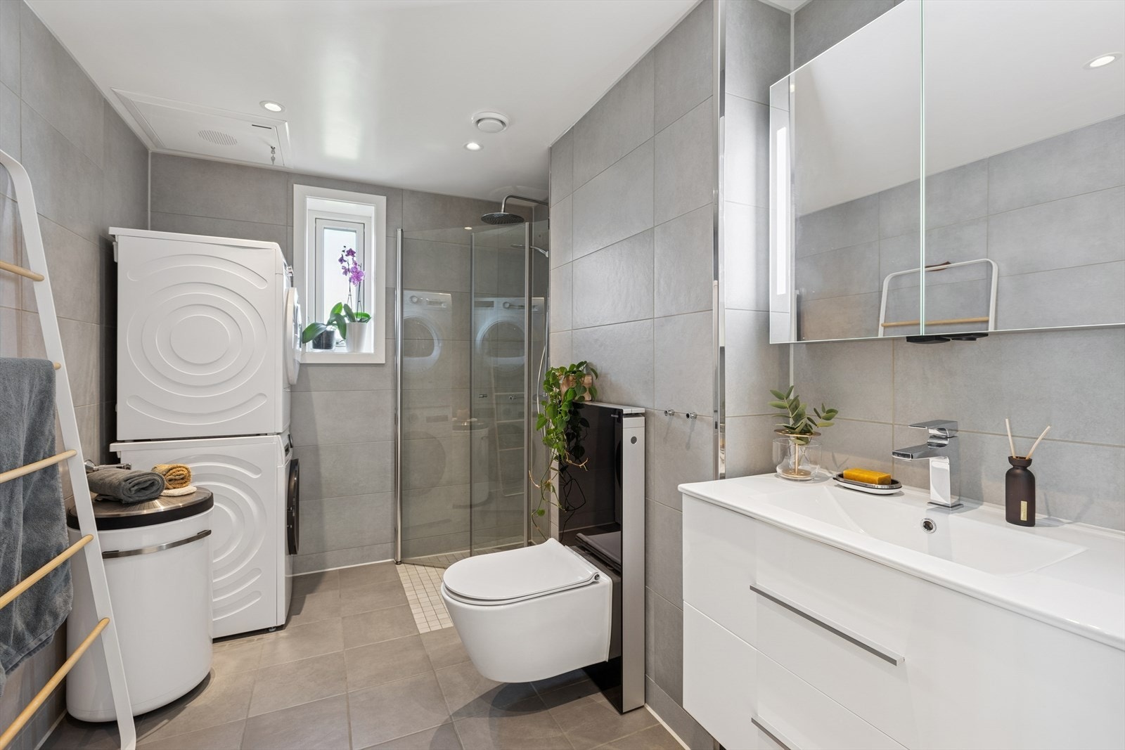 Videre er rommet utstyrt med baderomsinnredning, veggmontert toalett med utenpåliggende sisterne og dusjhjørne med svingbare glassdører. Galleribilde