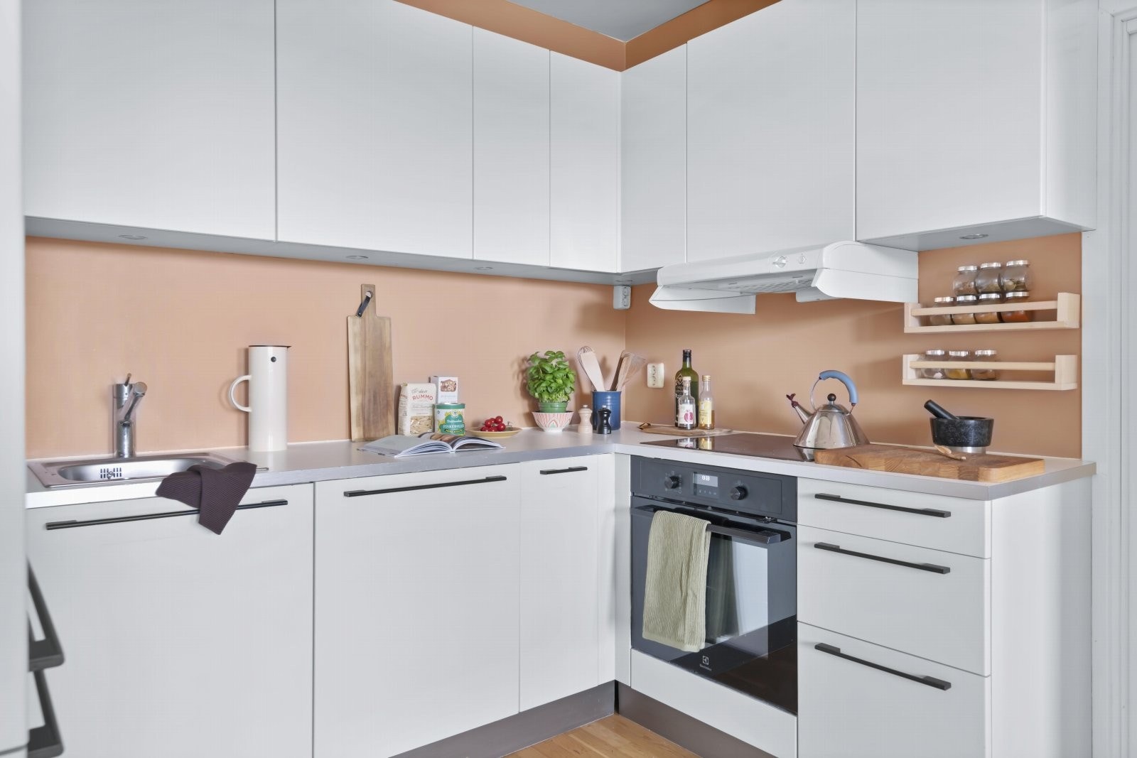 Laminat benkeplate med kantlist i stål, og nedfelt kum i rustfritt stål. Kjøkkenvegg er malt med våtromsmaling for å tåle sprut fra stekesone og kum. Galleribilde