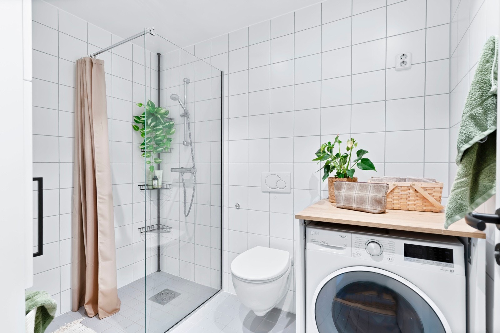 Flislagt baderom utført i lyse farger med vannbåren i gulv, og opplegg for vaskemaskin. Galleribilde