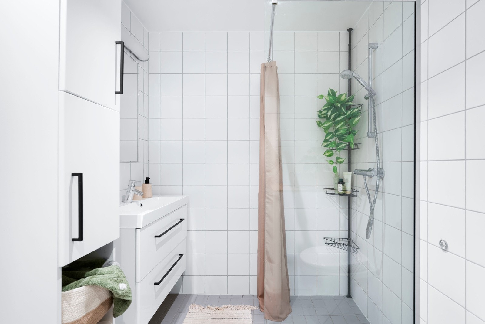 Oppbevaring i servantskap og speil på vegg. Dusjhjørne med glassvegg og dusjforheng samt veggmontert klosett. Galleribilde