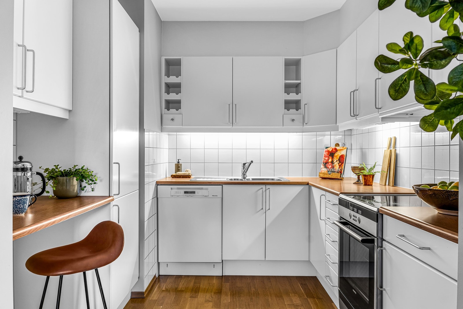 Kjøkkenet har en moderne innredning med lyse, slette fronter og benkeplate i laminat/finert spon. Nedfelt oppvaskkum i rustfritt stål med ettgreps blandebatteri gir et funksjonelt og rent uttrykk. Galleribilde