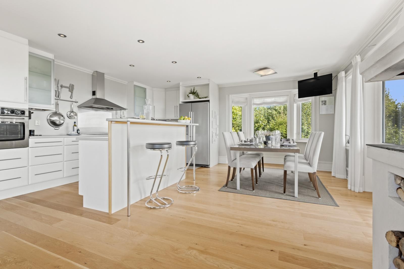 Hvit kjøkkeninnredning med slette fronter og stålbeslag. Galleribilde