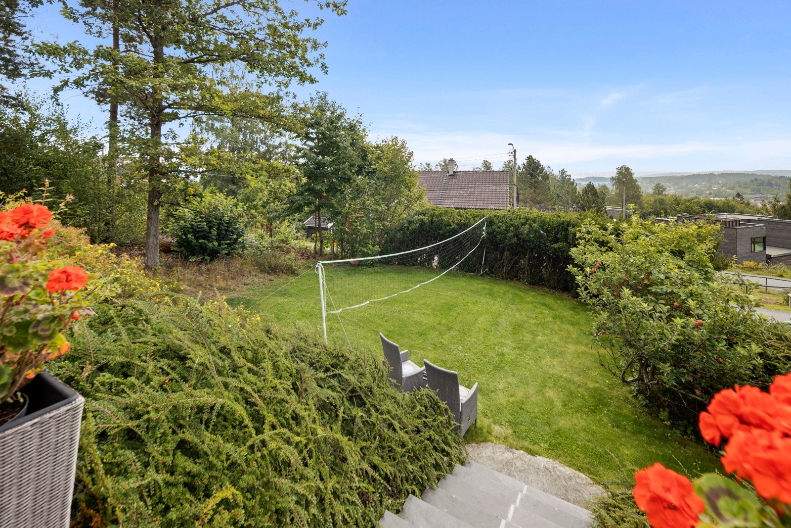 Pent opparbeidet hage med gressplen og beplantninger. Adkomst fra flisbelagt trapp ved svømmebassenget Galleribilde