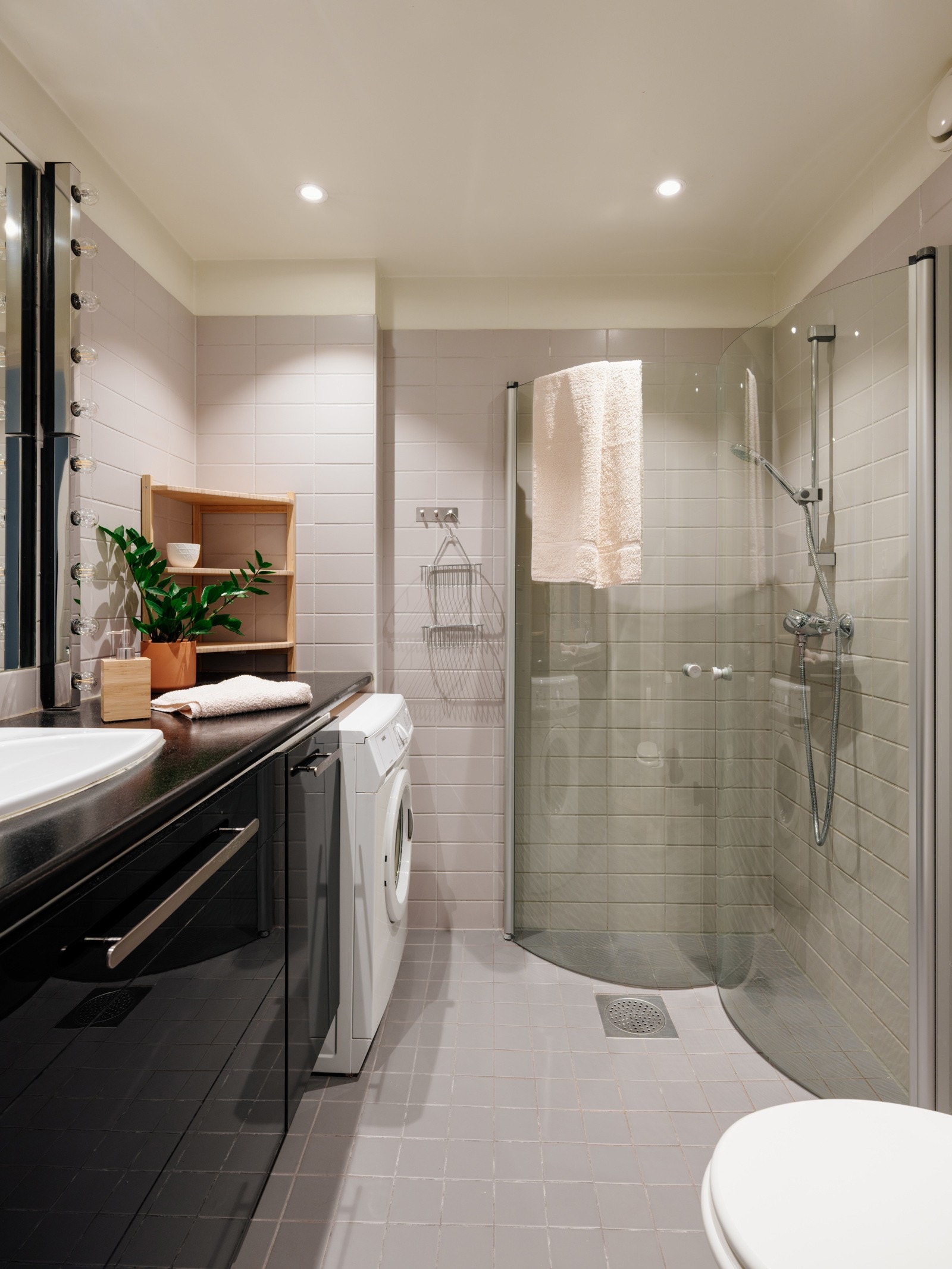 Baderommet inneholder servant med underskap, stort speil med belysning, gulvstående, toalett og dusjhjørne. Galleribilde