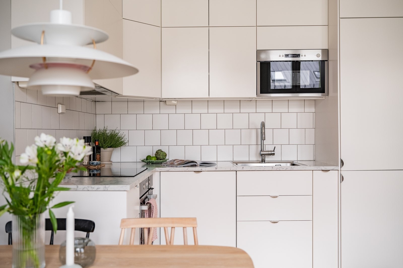 Kjøkkeninnredning med glatte fronter, belysning under overskap og fliser på vegg over benkeskap. Galleribilde