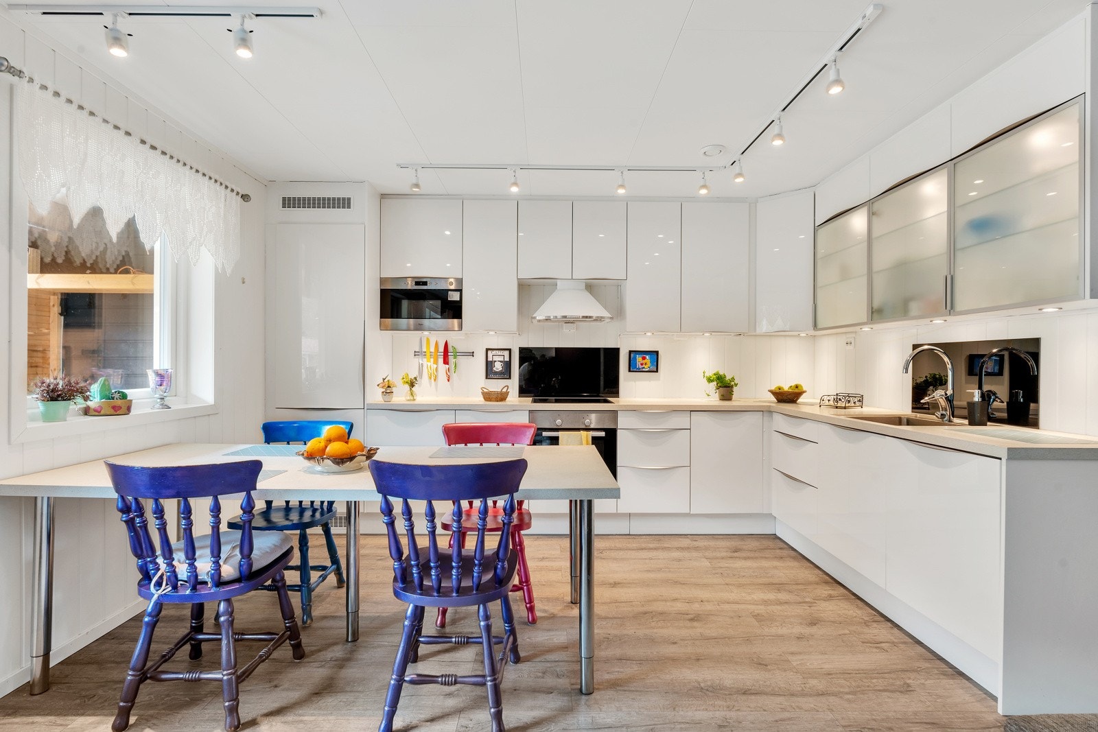 Moderne kjøkken med glatte fronter og benkeplate av laminat. Integrert stekevon, platetopp, oppvaskmaskin, mikrobølgeovn og kjøleskap med fryser. Galleribilde