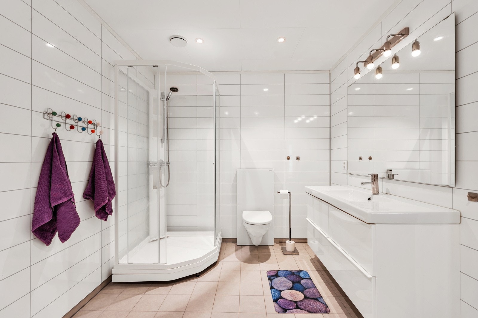 Lyst bad med fliselagt gulv, våtromsplater, dusjkabinett og gulvvarme. Galleribilde