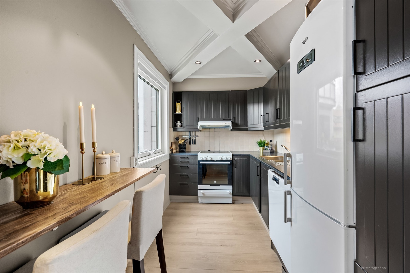 Profilert IKEA-kjøkkeninnredning med over- og underskap samt høyskap i mørk utførelse Galleribilde