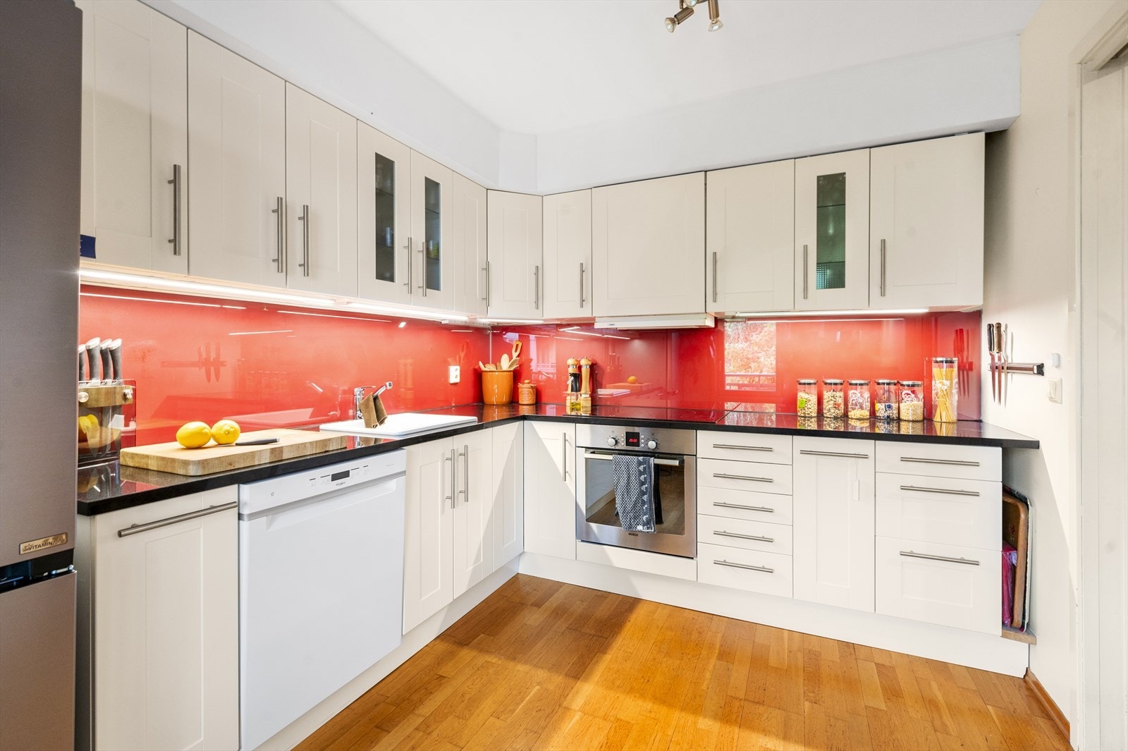 Separat kjøkken med innredning fra 2006, med hvite fronter og sort benkeplate i granitt Galleribilde