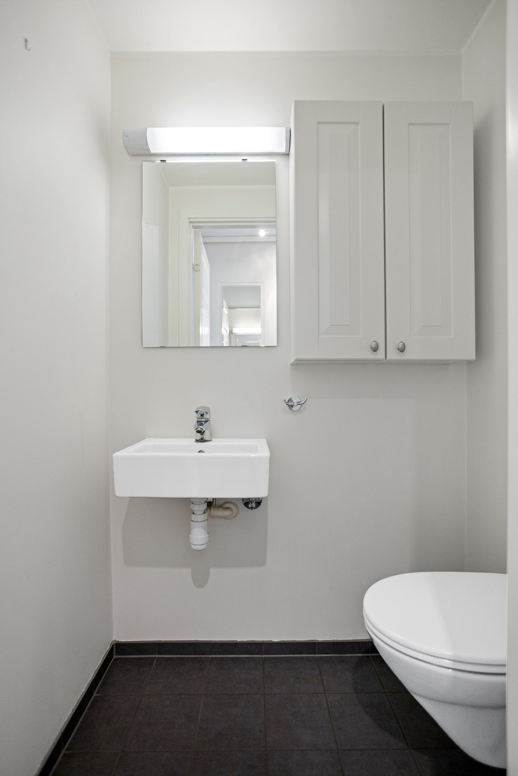 Gjestetoalettrommet, med inngang fra entreèn, sørger for at leiligheten har to toaletter. Varmekablene under det flislagte gulvet sørger for, på samme måte som på baderommet, for god varme til gulvet. Det er vegghengt toalett og servant. Galleribilde