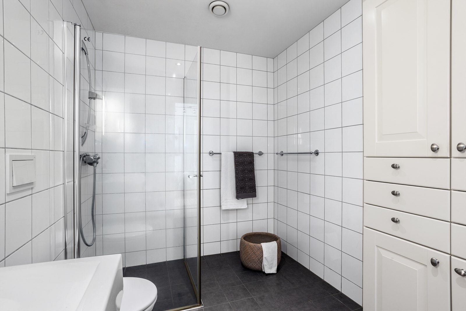 Badet har også vegghengt WC med skjult sistere. Dusjen har dusjvegger med glassdører av herdet glass. Glassdørene har funksjon med inn-/utsving. Galleribilde