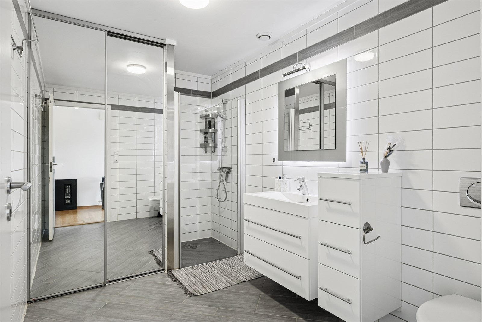 Pent flislagt bad med varmekabler. Vaskemaskin skjult bak skyvedør. Galleribilde