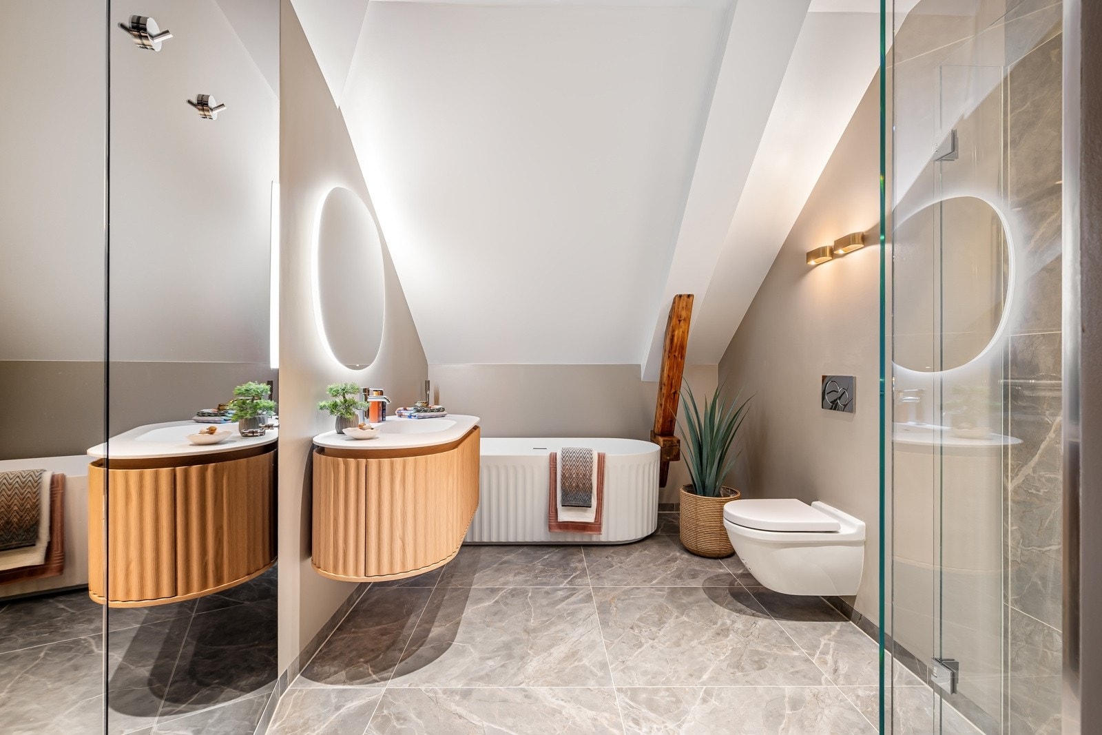Badet har adkomst fra hallen og er innredet med et stilig, frittstående designbadekar med hvite rillefronter. Oval servant i corian på eikemøbel med ovale rillefronter matcher badekaret. Galleribilde