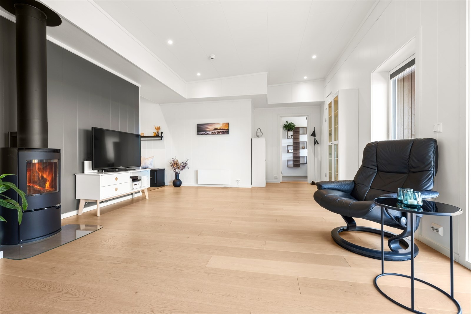 Praktisk og stemningsskapende vedovn i stuen. Moderne kontrastvegg. Galleribilde