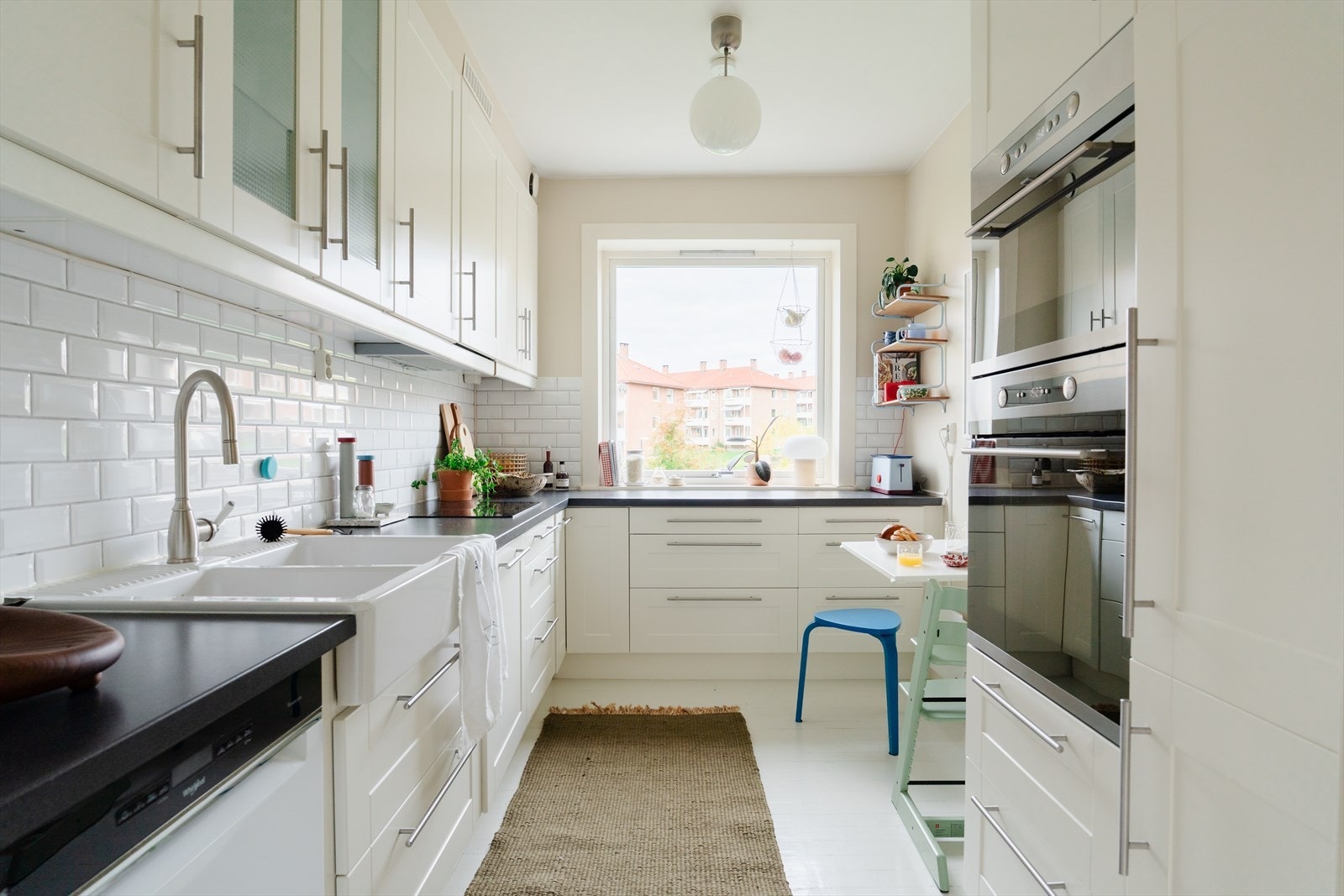 Lys og pen kjøkkeninnredning med profilerte fronter, fliser på vegg over benkeskap og laminat benkeplate Galleribilde